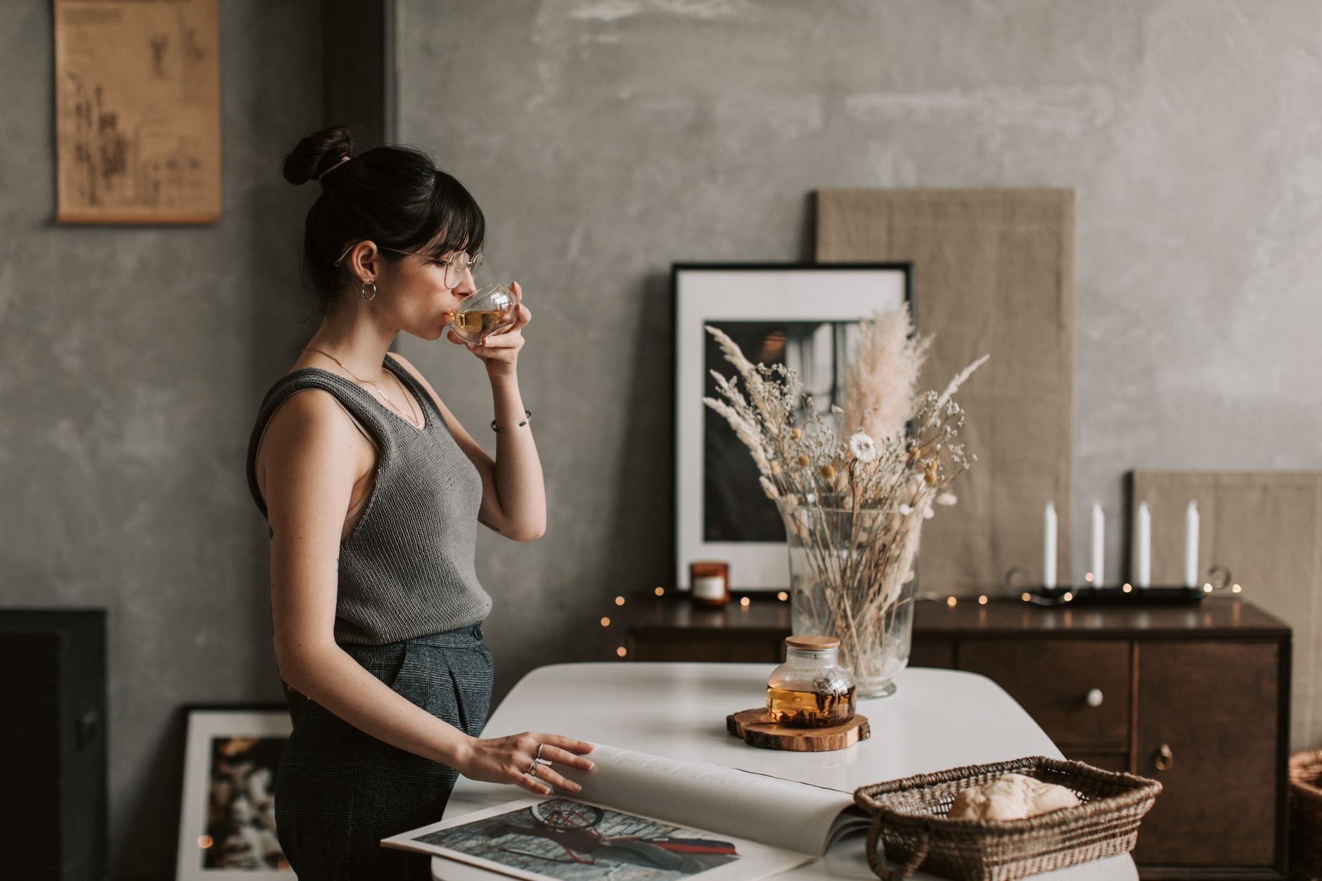 Woman enjoying tea in a cozy, stylish room with warm lighting and decor.